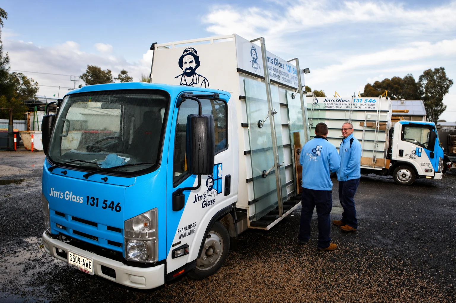 Jim's Glass team members beside branded glass service vehicles