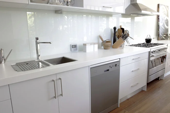 Light-coloured glass splashback fitted behind a kitchen bench